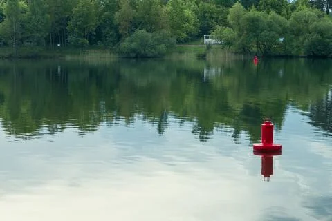 Red navigation buoy floating on the calm water surface of a scenic river wi.. Stock Photos