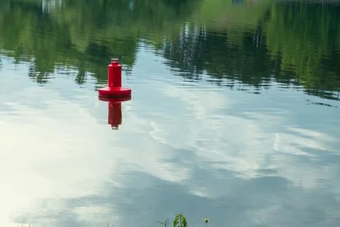 Red navigation buoy floating on the calm water surface of a scenic river wi.. Stock Photos