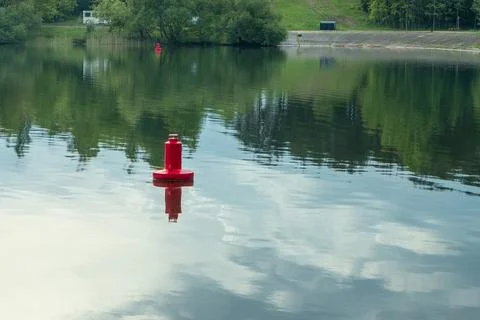 Red navigation buoy floating on the calm water surface of a scenic river wi.. Stock Photos