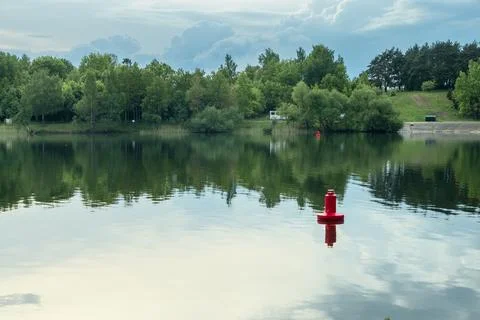 Red navigation buoy floating on the calm water surface of a scenic river wi.. Stock Photos