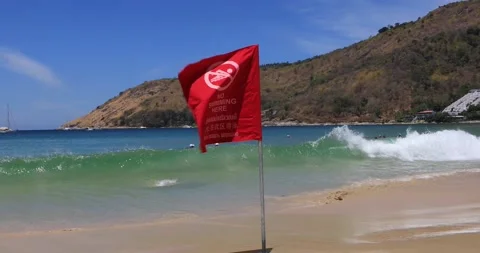 Red «No Swimming here» flag waving in the wind, blue sea waves Andaman Sea Stock Footage 149455282