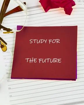 A red note reading study for the future rests on lined paper beside a pair .. Stock Photos