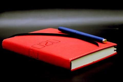 Red notebook 2020 and blue pen, story book with black and gray background Stock Photos