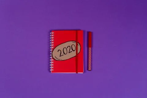 Red notebook with 2020 bubble on the violet background. Stock Photos