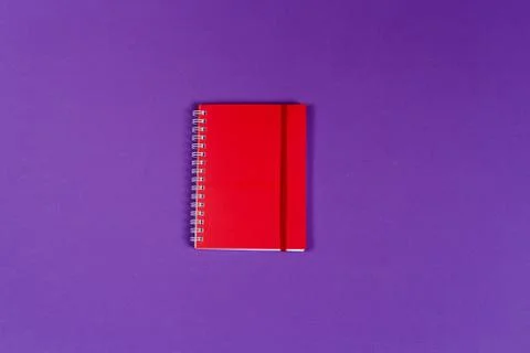 Red notebook on the dark violet background. Stock Photos