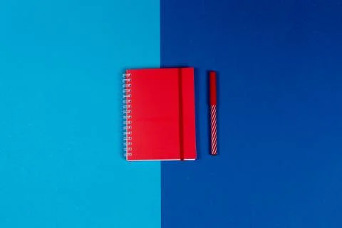 Red notebook with pen on the blue background. Stock Photos