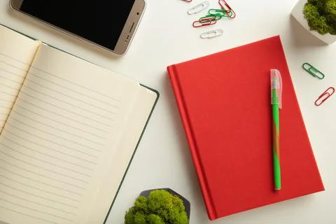 Red notebook with smartphone on grey background. Stock Photos