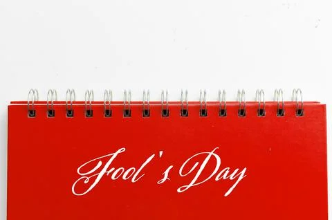 Red notebook with text FOOL'S DAY on white background. Stock Photos
