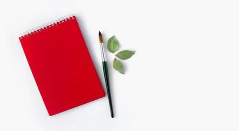Red notepad with a paintbrush on a white background. Top view, layout. Stock Photos
