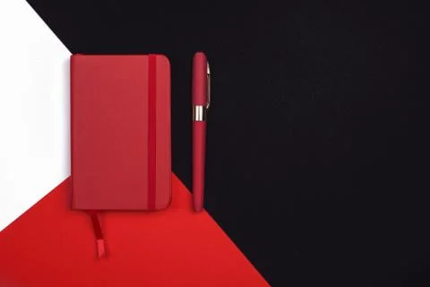 Red Notepad with pen on red, white and black background. Top view. Stock Photos