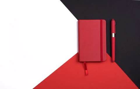 Red Notepad with pen on red, white and black background. Top view. Stock Photos