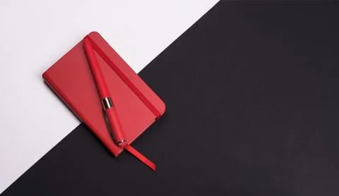 Red Notepad with pen on white and black background. Top view. Stock Photos