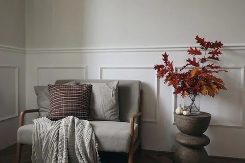 Red oak tree leaves, branches in vase on modern curved wooden side table. Linen Stock Photos