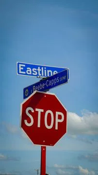 Red octagonal stop sign mounted beneath blue street signs at an intersectio.. Stock Photos