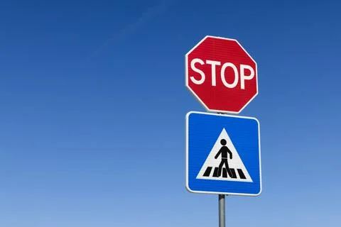 A red octagonal STOP sign positioned above a blue triangular pedestrian cross 스톡 사진