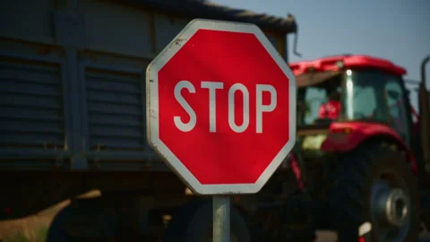 Red octagonal stop sign prominently featured in front of agricultural machi.. Stock Footage 344809925