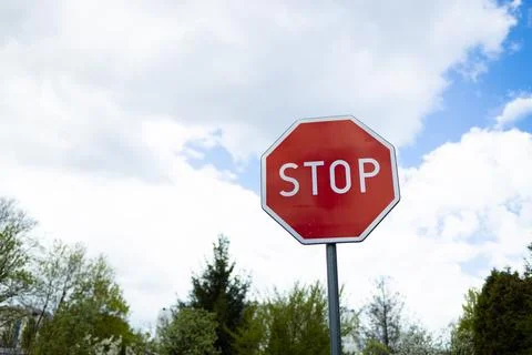 Red octagonal Stop traffic sign against beautiful blue sky with clouds. Stock Photos