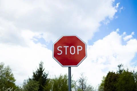 Red octagonal Stop traffic sign against beautiful blue sky with clouds. Stock Photos