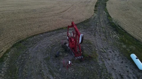 Red oil pump jack working in the countryside of Alberta. Wide angle aerial Stock Footage 196777799