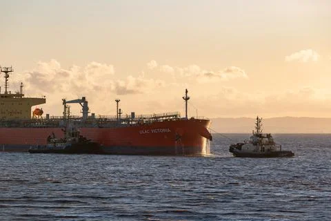 A red oil tanker being helped by some tugs Stock Photos