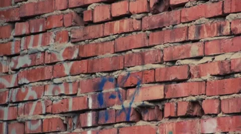 Red old brick's wall with graffiti running up Stock Footage 921525