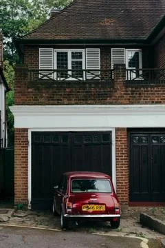 Red oldstyle Mini parked in front of the garage 스톡 사진