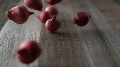 Red onions falling and rolling on a table. Slow Motion. Stock Footage 84924916