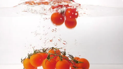 Red organic cherry tomatoes falling and splashing into fresh water Stock Footage 171181403
