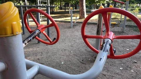 Red outdoor exercise equipment with circular handles in a city park. Stock Footage 342994297