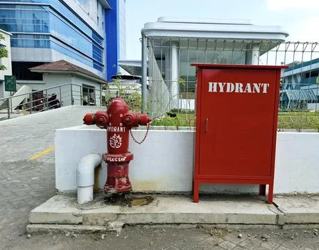 Red outdoor fire hydrant and storage box standing on concrete base near mod.. Stock Photos