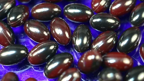 Red oval capsules in a shiny shell extremely close-up. Real time, natural light, Stock Footage 144855178