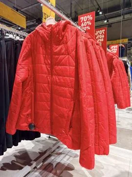 Red padded jackets displayed on racks in a clothing shop present a practica.. Stock Photos