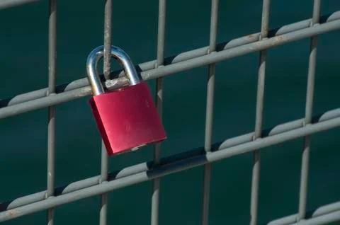 Red padlock on metallic grid Foto stock