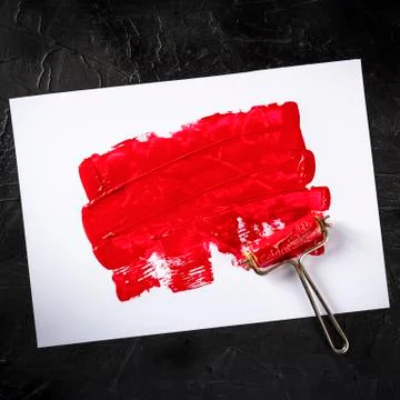 Red paint background with a roller, an abstract texture with a place for text Фото