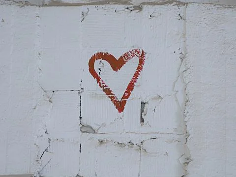 Red paint drawing of a heart shape on the white brick wall background Stock Photos