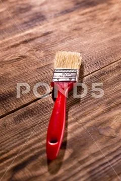 Red paintbrush on burnt wooden background Stock Photos