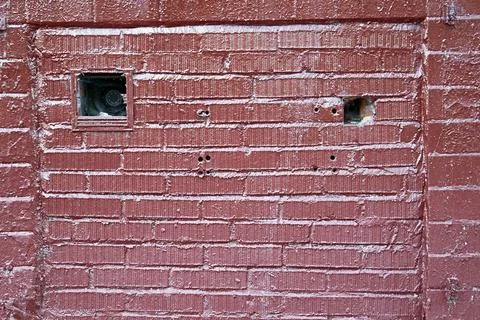 Red painted brick wall texture with old small openings and rough surface Stock Photos