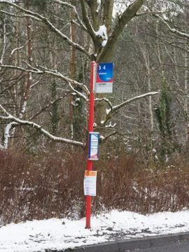 A red painted bus stop pole and flag in the snow Stock Photos
