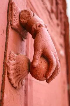 Red painted doorknocker with hand shape on red wooden door Photos