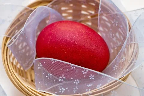 A red painted Easter egg lies in a wicker basket Stock Photos
