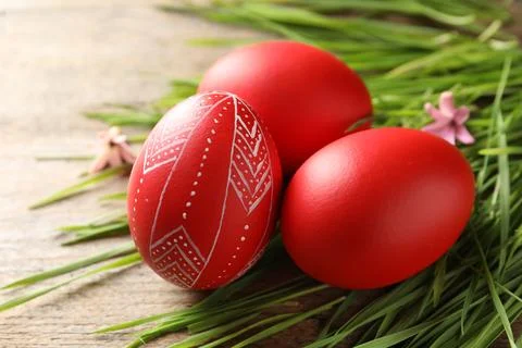 Red painted Easter eggs and green grass on wooden table, closeup Stock Photos