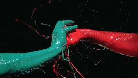 Red painted hand punching on green painted palm. Slow Motion. Stock Footage 72867916