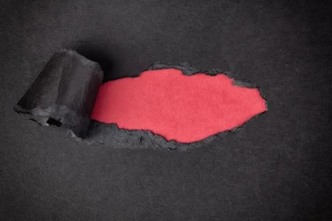 Red paper background appearing behind torn black paper Stock Photos