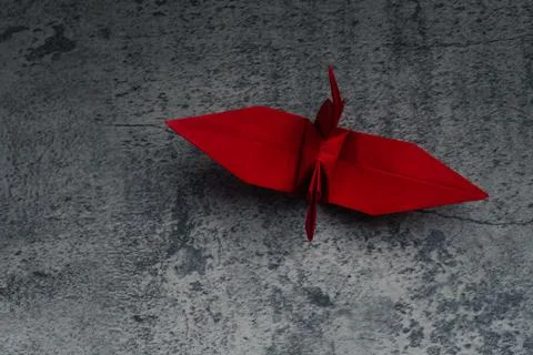 Red paper crane on gray background. Symbol of hope. Stock Photos