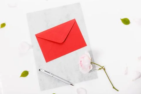 Red paper envelope with blank note and Valentines pink rose on white backgr.. Stock Photos