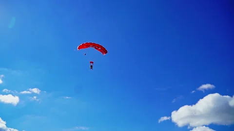 Red parachute with tandem quickly approaching ground.  Stock Footage 230921492