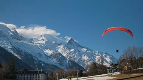 Red paraglider soaring low over Chamonix valley with Mont Blanc massif in Vídeo Stock 333986718