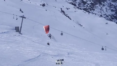 A red paraglider with tourists gently sails through a snow-covered gorge pa.. Stock Footage 296626207