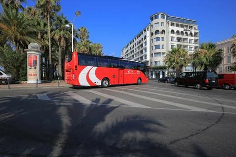 Red passenger bus rides down the street in .. Stock Photos