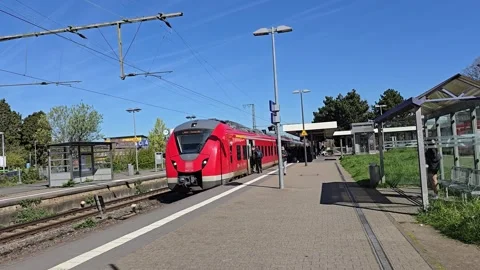 Red passenger train at a station platform under a clear blue sky railway. Stock Footage 341878623